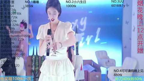 Media: A video of a young East Asian woman in a white, ruffled dress, singing into a microphone on a stage with blue lighting and audience members in the background.