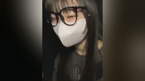 Media: A digitally manipulated video depicts a person with long black hair, wearing black glasses, a white mask, and a dark shirt, against a dark background.