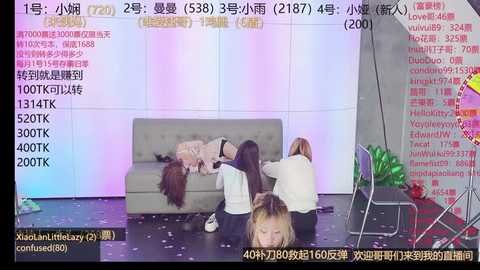 Media: Video of a group of young women in a studio setting, wearing casual clothing, sitting on a grey couch, with text overlay from a video streaming platform.