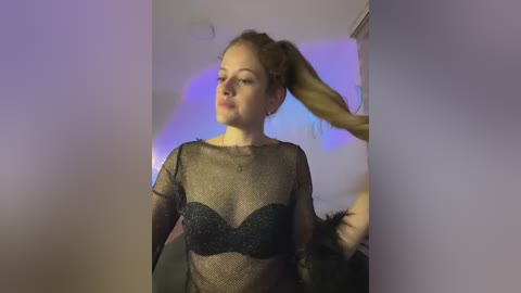 Media: Video of a fair-skinned, red-haired woman in a sheer black mesh top, holding her hair up in a ponytail, in a dimly lit room with purple lighting.