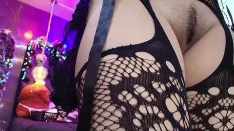 Media: Video of a person wearing a black fishnet bodysuit, showcasing a large, exposed vulva. Background features a colorful, festive room with a Buddha statue and Christmas lights.