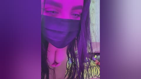 Media: A video of a woman with long, wet hair, wearing a black face mask, and a floral-patterned top. The background is dimly lit with purple and pink hues, suggesting a nightclub or party setting.