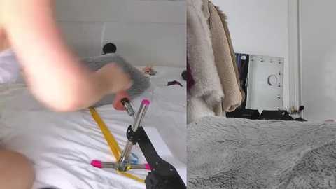 Media: Video: A man wearing a gray shirt uses a black vacuum cleaner on a white bed. The room is minimalistic with beige blankets and a white wall, featuring a large mirror.