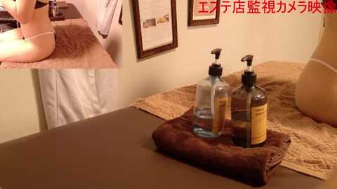 Media: Video of a spa room with a woman's legs in white lingerie, framed artwork, and three bottles of lotion on a brown tray.