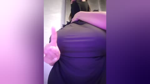 Media: A video of a woman with a light complexion, wearing a black dress, giving a thumbs-up gesture. The background is blurred, featuring a gradient of purple and pink hues.