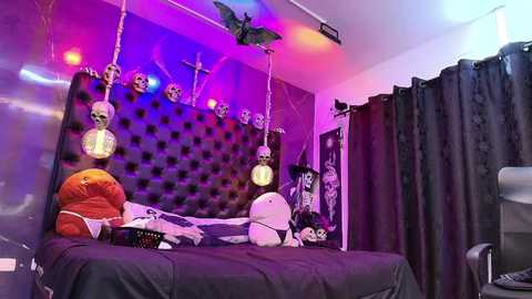 Media: A vibrant, Halloween-themed bedroom with a tufted black headboard adorned with skulls, colorful lights, and plush toys.