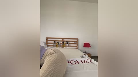 Media: A video of a minimalist bedroom with a wooden headboard, white bed, red lamp, and a white pillow with \"CHART\" in red letters.