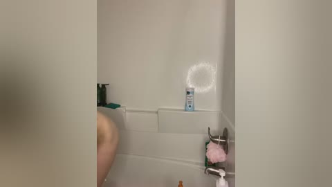 Media: Video of a beige-tiled shower stall with a white showerhead emitting steam. A person with light skin and short hair is visible from the back, standing in the shower.