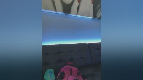 Media: A video of a person wearing a pink jacket, lying on a tufted, gray couch, looking out a window at a clear, blue sky with a thin, white horizon.