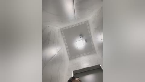 Media: Video of a modern, dimly lit interior ceiling with a rectangular light fixture and textured white walls, capturing a minimalist, clean aesthetic.