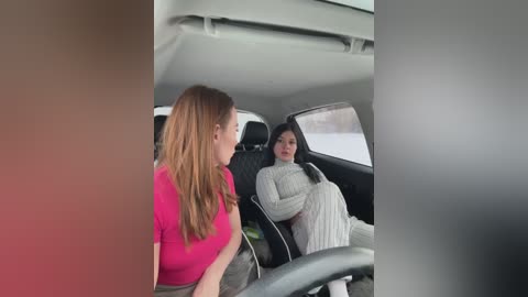 Media: Video of a woman in a pink shirt driving a car, with a woman in a grey sweater in the passenger seat, looking out the window.