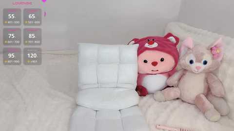 Media: Video of a plush pink fox and a soft gray bunny on a white, quilted chair, with a virtual reality display showing health and stamina bars in the background.