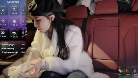 Media: Video of a young woman in a car, wearing a white coat and black headband, typing on a phone, with a digital clock and social media icons in the background.