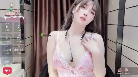 Media: A video of a young Asian woman with fair skin, wearing a pink lace lingerie top and a stethoscope, posing seductively in a bathroom with tiled walls.