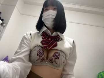 Media: Video of a woman in a white shirt, red striped tie, face mask, and a revealing lace bra with floral embroidery, captured from a low angle, in a simple indoor setting.