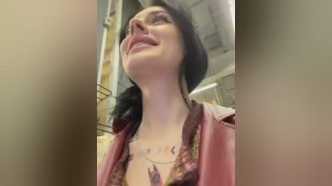 Media: Video of a smiling woman with pale skin, dark hair, and a floral patterned top, standing indoors.