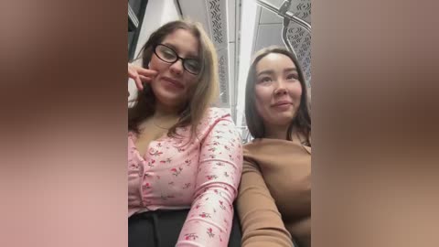 Media: Video of two women, one with glasses and a floral blouse, the other in a beige sweater, smiling in a bathroom with ornate decor.