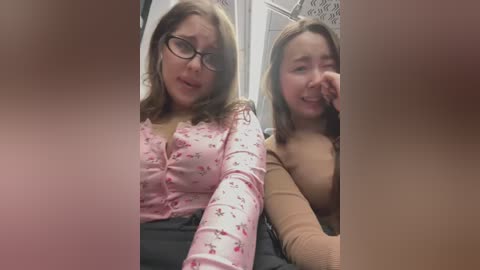 Media: Video of two women in a subway, smiling; one in glasses, light pink floral blouse, and black pants; the other in a beige top.