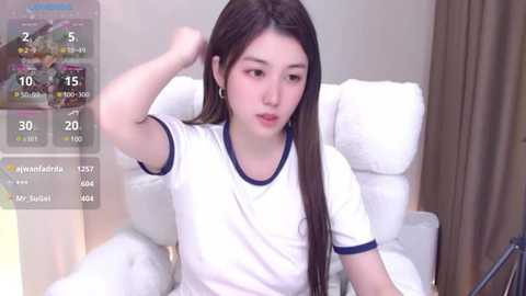 Media: A video of a young East Asian woman with long dark hair, wearing a white T-shirt, sitting on a white chair in a modern room with beige curtains. A digital screen overlay shows her stats, including \"Guanfeng\" and \"Kungfu Girl.\