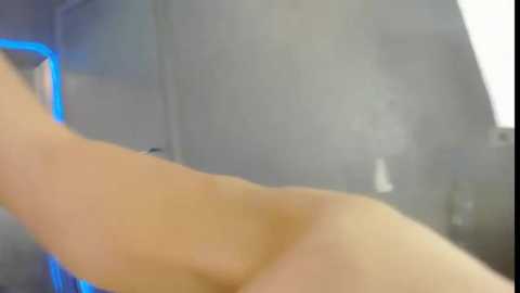 Media: A blurry, out-of-focus video shows a nude, light-skinned person lying on their side, with a blue light in the background suggesting a hospital or medical setting. The person's arm is raised.