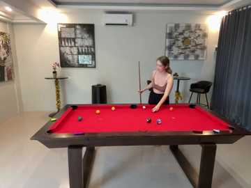 Media: Video of a woman playing pool in a modern room with gray walls, an air conditioner, and black and white art.