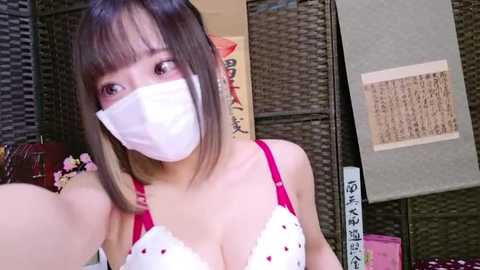 Media: Video of an Asian woman with straight, shoulder-length brown hair, wearing a white lace bra with red polka dots, a face mask, and a grey kimono with Japanese calligraphy.