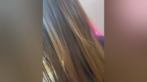 Media: Video of a person's shoulder-length, straight, light brown hair, slightly tousled, with strands falling in different directions. The background is blurred, featuring a mix of muted colors. The image captures a casual, natural look.