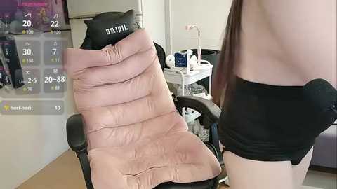 Media: A video shows an overweight person in a black strapless dress sitting on a pink puffy chair in a cluttered room with medical equipment and a monitor displaying health stats.