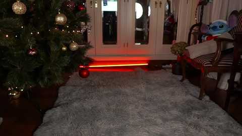 Media: Video of a cozy living room with a lit Christmas tree, a plush white rug, a red glowing LED strip under a table, and a stuffed toy on a chair.