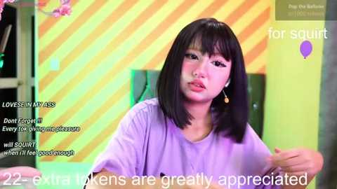 A video of an Asian woman with straight black hair and a light purple shirt, speaking in a studio with a vibrant, striped yellow-orange background. Text overlays mention \"22 views\" and \"every woman is appreciated.\