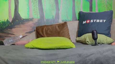 Media: Video of a bed with a green pillow, brown pillow, and \"MSTBET\" pillow, set against a forest mural.