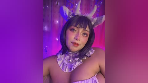 Media: Video of a young woman with shoulder-length dark hair, wearing a white ruffled choker and deer antler headband, standing against a purple and pink gradient background, showcasing her ample cleavage.