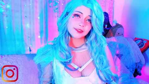 Media: Video of a smiling woman with long, wavy, turquoise hair, wearing a white lace top, posing in a brightly lit, neon-lit room with a plush toy.