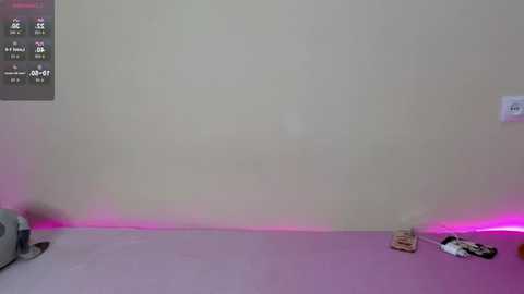 Media: A video of a beige wall with a pink light at the bottom, revealing a pair of black and white socks on a gray carpet.