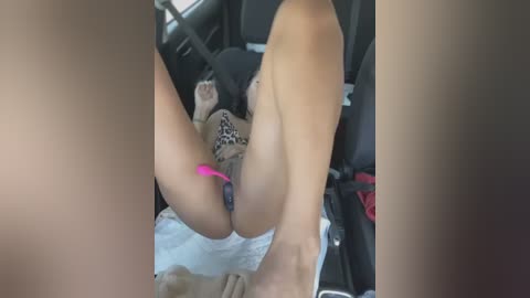 Media: A video of a woman with light skin, lying in a car, legs spread, wearing leopard-print underwear with a pink vibrator inserted into her vagina, in a sexual position.