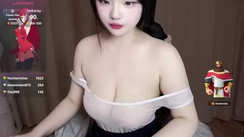 Media: Video of an East Asian woman with fair skin, dark hair, and large breasts, wearing a sheer white top and navy blue skirt, indoors.