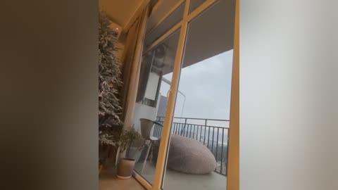 Media: A video of a modern balcony featuring a cozy, faux-fur beanbag, potted plants, and snow-dusted Christmas tree, with a misty, overcast sky as the backdrop.