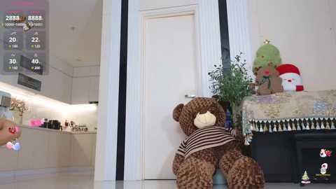 Media: A video of a plush brown teddy bear with a striped shirt, sitting against a white door in a modern kitchen with black accents.