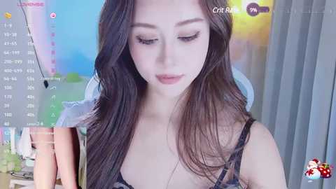 Media: A video of a young Asian woman with long, dark hair, wearing a black lace bra, in a room with colorful, abstract wall art.