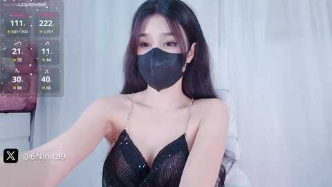 Media: A video of an East Asian woman with long black hair, wearing a black mask, black sequin dress, and a digital calendar overlay.