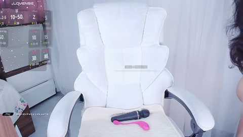 Media: Video of a white leather massage chair in a modern room with a calendar, a pink vibrator, and a black dildo on the table.