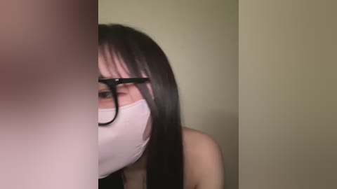 Media: A video of an Asian woman with long black hair, wearing glasses and a face mask, partially hidden by a blurred figure on the left.