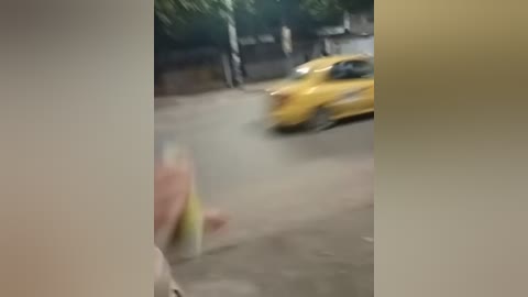 Media: A blurred video of a person in a yellow shirt walking on a street with a yellow taxi in the background. The image is grainy and slightly out of focus.