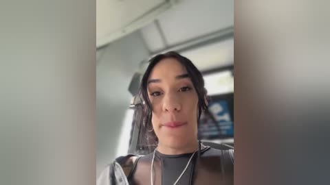 Media: Video of a young Asian woman with medium-length black hair, wearing a black jacket and a silver necklace, seated in a train with blurred background.