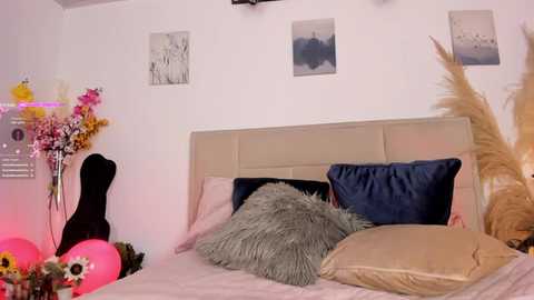 Media: Video of a cozy bedroom with a white headboard, blue pillows, pink flowers, and decorative items.