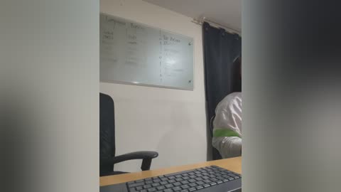 Media: Video of a dimly lit office with a whiteboard listing tasks, a black office chair, a wooden desk, and a person in a green shirt partially visible.