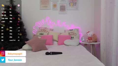 Video of a pink neon-lit bedroom with a white bed, plush toys, and a festive Christmas tree in the background.