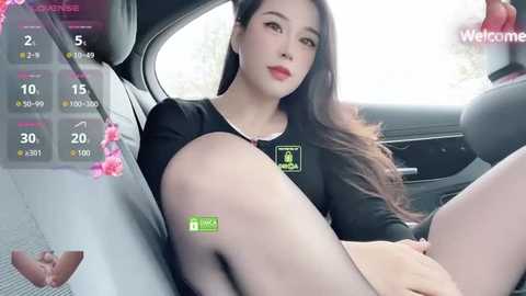 Media: Video of an East Asian woman with long dark hair, wearing a black top, sitting in a car. She has a slender physique and fair skin.