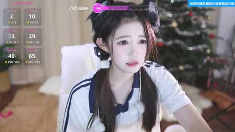 Media: Video of a young East Asian woman with fair skin, wearing a white sailor uniform, black cat ears, and sitting in a cozy, Christmas-decorated room.