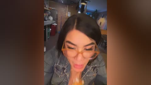 Media: A video of a woman with dark hair, wearing glasses and a denim jacket, drinking a beer in a dimly lit, cozy bar with brick walls and wooden decor.